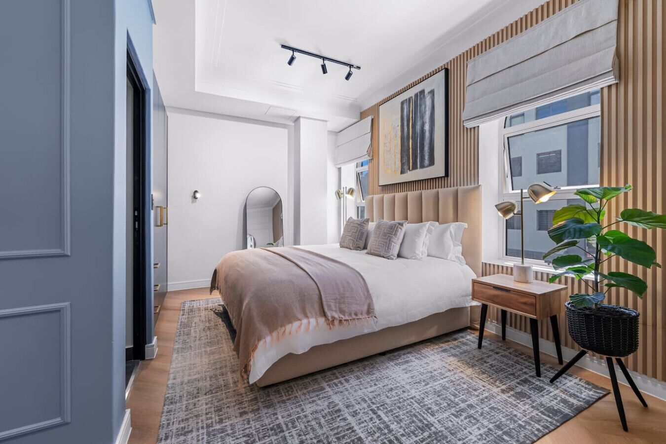 A modern bedroom with a large bed, bedside table, and a potted plant.