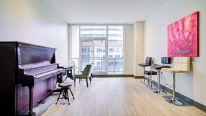 Ein geräumiges Zimmer mit einem Flügel, einem großen Fenster mit Blick auf die Stadt und einer modernen Bar.