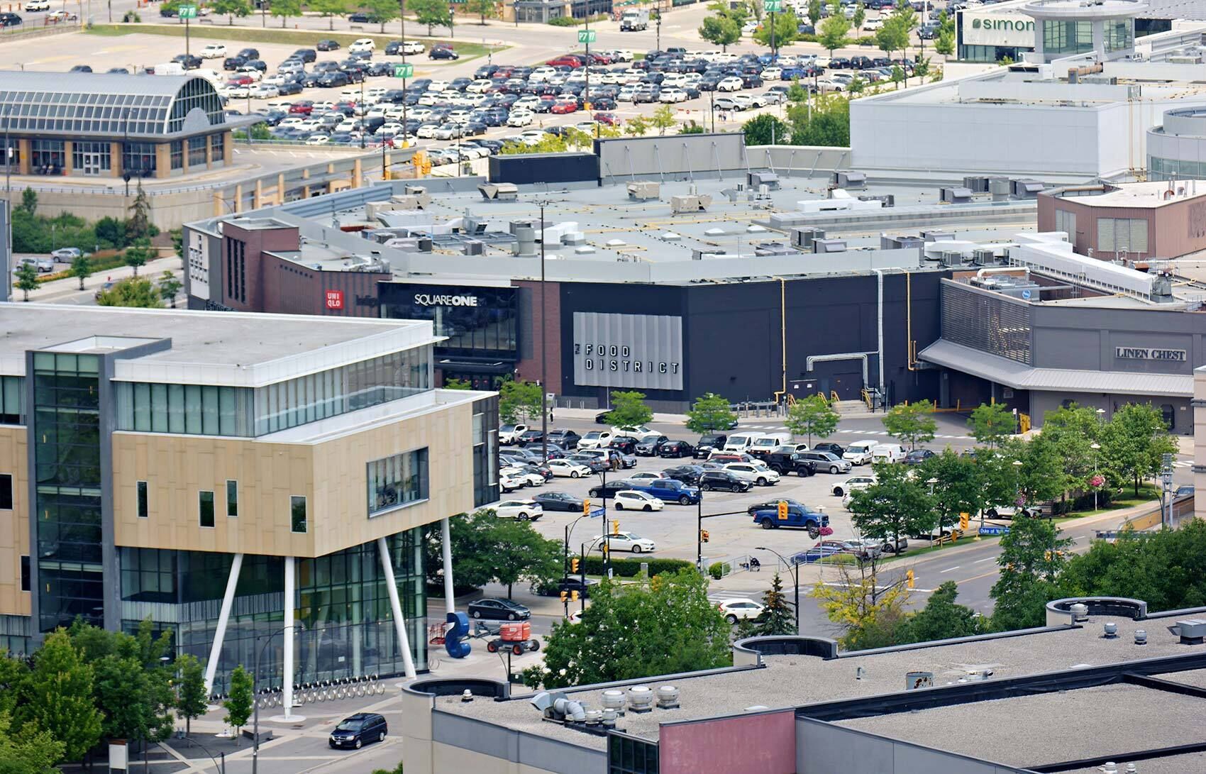 A commercial building with multiple floors, a parking lot, and a large sign for 'SQUAREONE'.