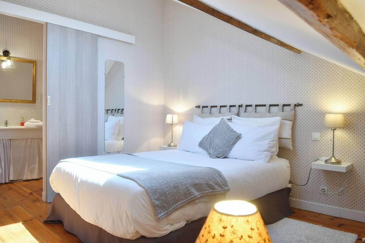 Une chambre avec un grand lit, des lampes de chevet, un miroir et un plafond en bois.