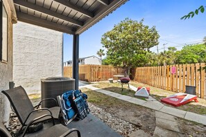 Eine überdachte Terrasse mit Gartenmöbeln, einem Grill und einem Holzzaun.