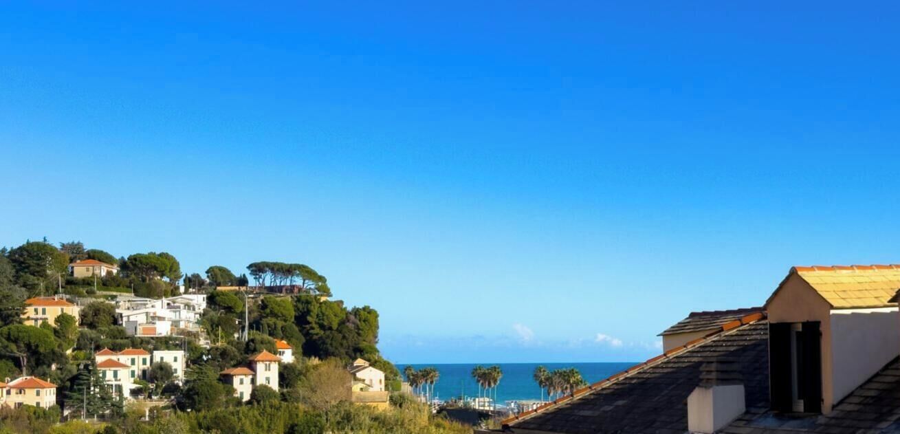 Eine Küstenstadt mit Häusern an einem Hügel, einem klaren Himmel und dem Meer in der Ferne.