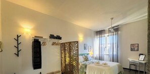 Hotellihuone, jossa on sänky, työpöytä, tuoli, vaatekaappi ja koristeellinen sermi.