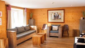 A wooden-paneled room with a sofa, two chairs, a small table, and a framed picture on the wall.