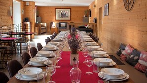 A long dining table set for a meal in a room with wooden walls and a clock.