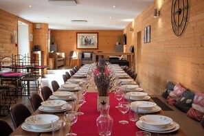 A long dining table set for a meal in a room with wooden walls and a clock. - Group gîte near La Bresse. Sleeps 20-41 (Ventron)