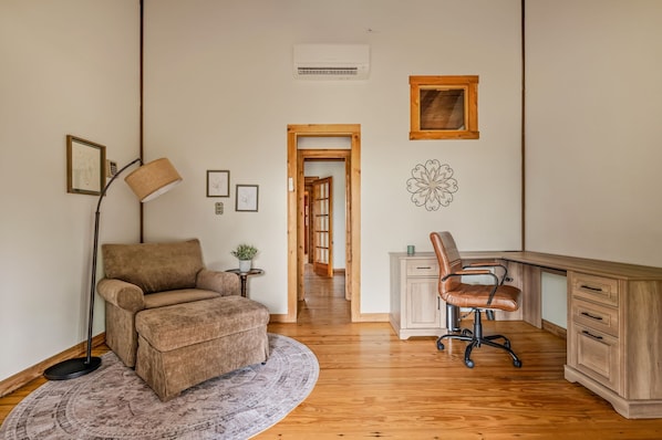 Ett rum med en brun soffa, ett skrivbord med en stol, en lampa och en rund matta.