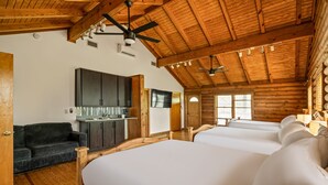Una camera in stile baita con un letto grande, un divano, una TV e una ventola a soffitto.