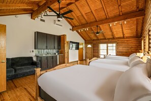 Ein Blockhaus-Zimmer mit einem großen Bett, einer Couch, einem Fernseher und einem Deckenventilator.