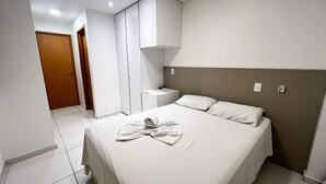 Una habitación de hotel con cama, mesita de noche, armario y puerta.
