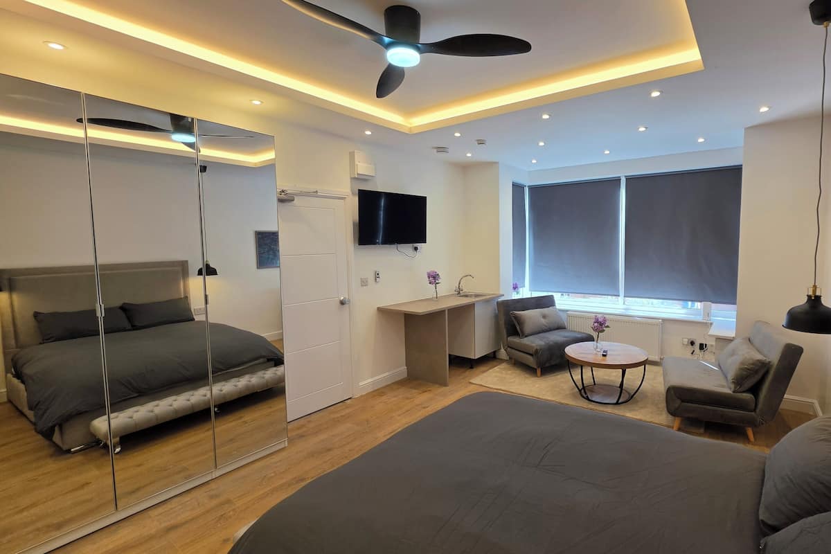Ein modernes Schlafzimmer mit einem großen Bett, einem Schreibtisch, einem Stuhl und einem kleinen Tisch.