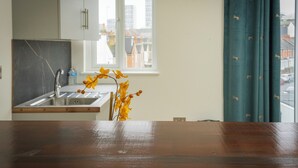 A kitchen with a sink, a window, and a vase with yellow flowers.