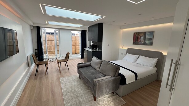 A modern bedroom with a bed, sofa, and dining table.