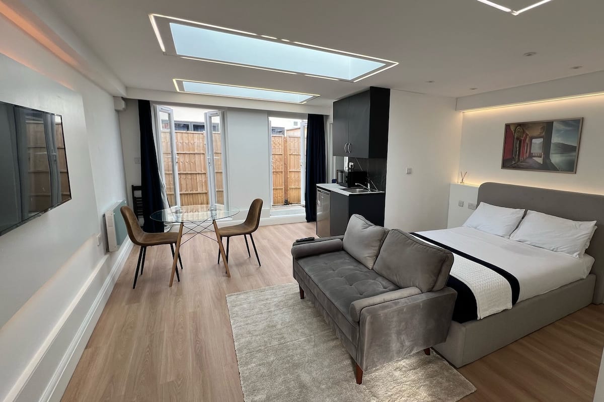 Ein modernes Schlafzimmer mit Bett, Sofa und Esstisch.