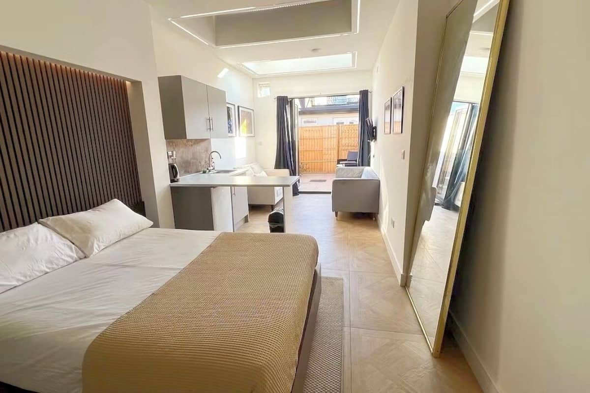 Ein modernes Hotelzimmer mit einem großen Bett, einem kleinen Schreibtisch, einem Spiegel und Blick nach draußen.
