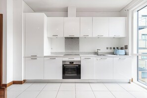 Eine moderne Küche mit weißen Schränken, einem eingebauten Ofen und einem Fenster, das für natürliches Licht sorgt.
