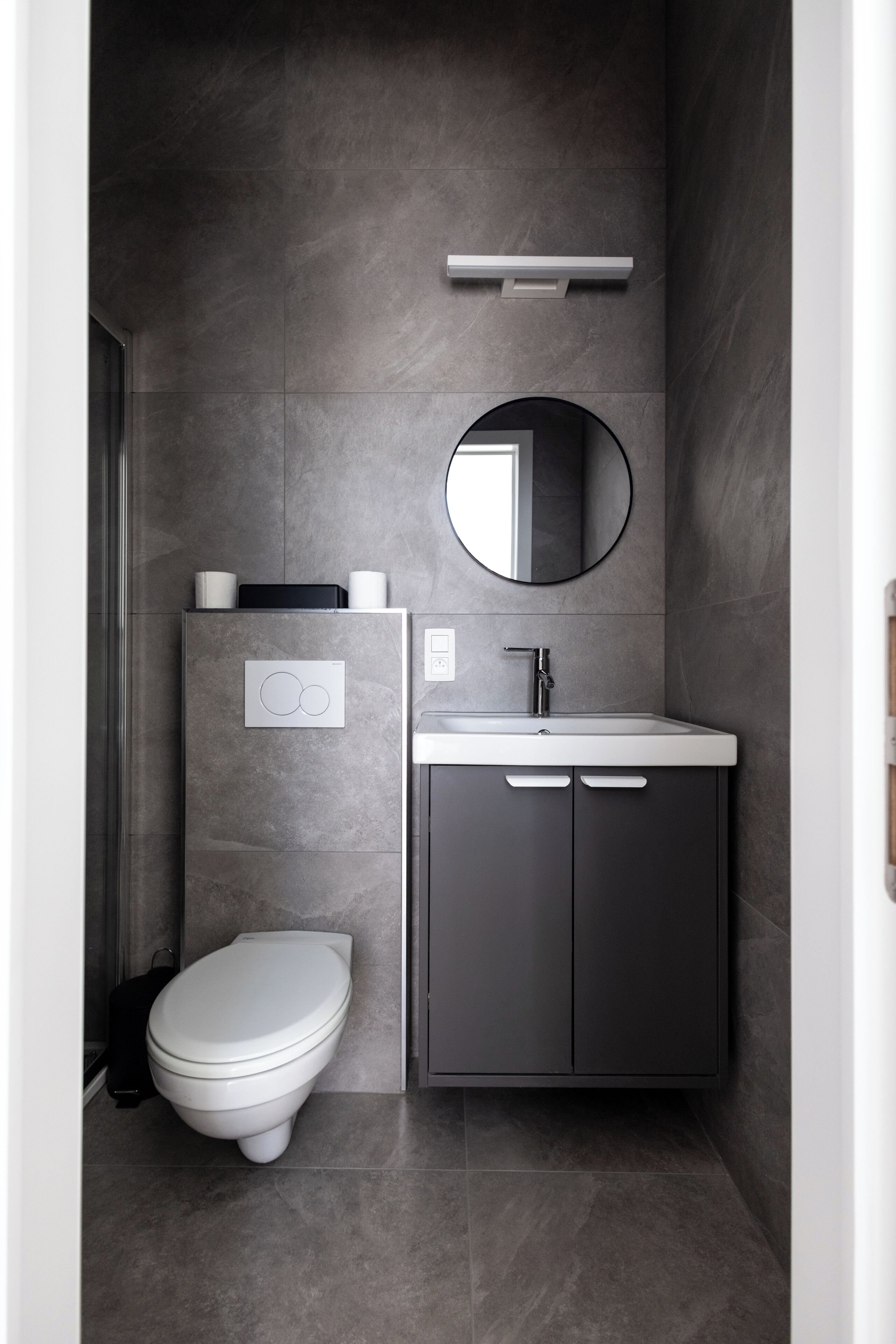 A modern bathroom with a toilet, sink, and mirror.