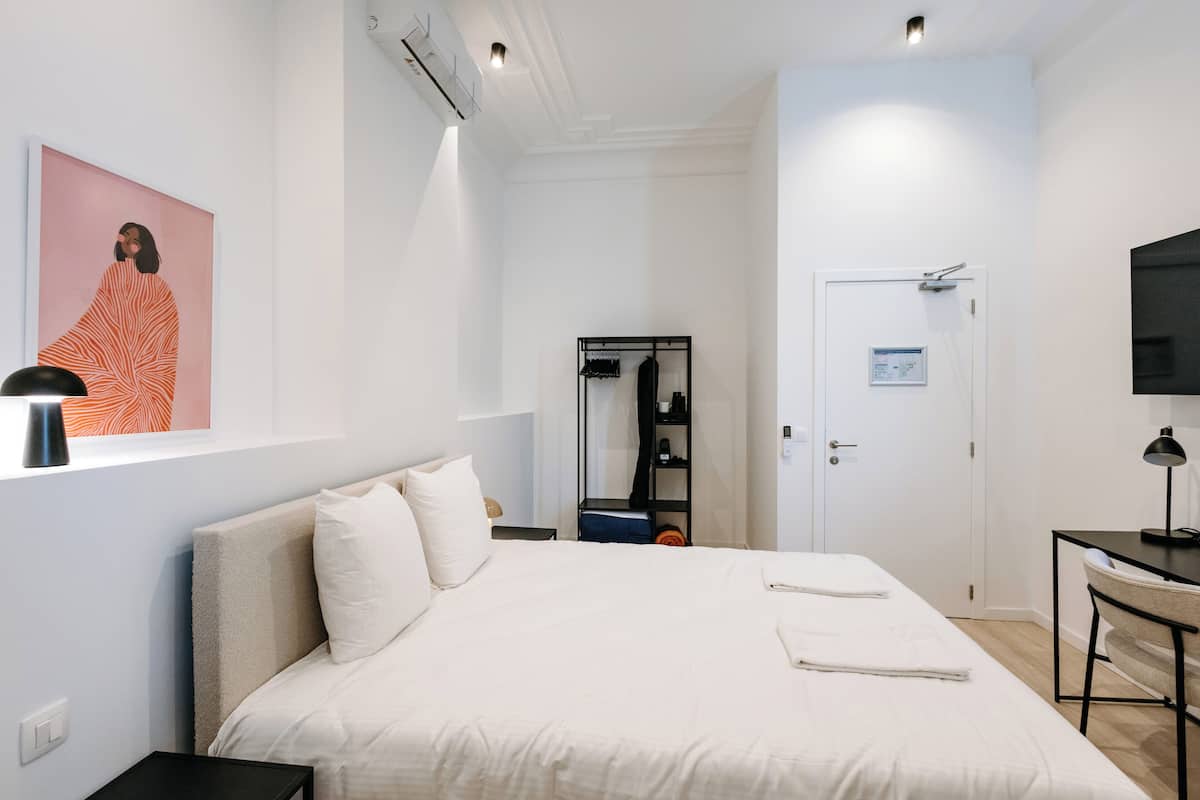 Une chambre d’hôtel moderne équipée d’un grand lit, d’un bureau, d’une armoire et d’un téléviseur.