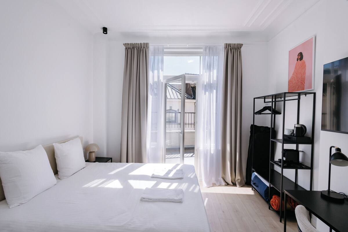 Une chambre d’hôtel comprenant un lit, un bureau, une chaise, une armoire et un balcon.