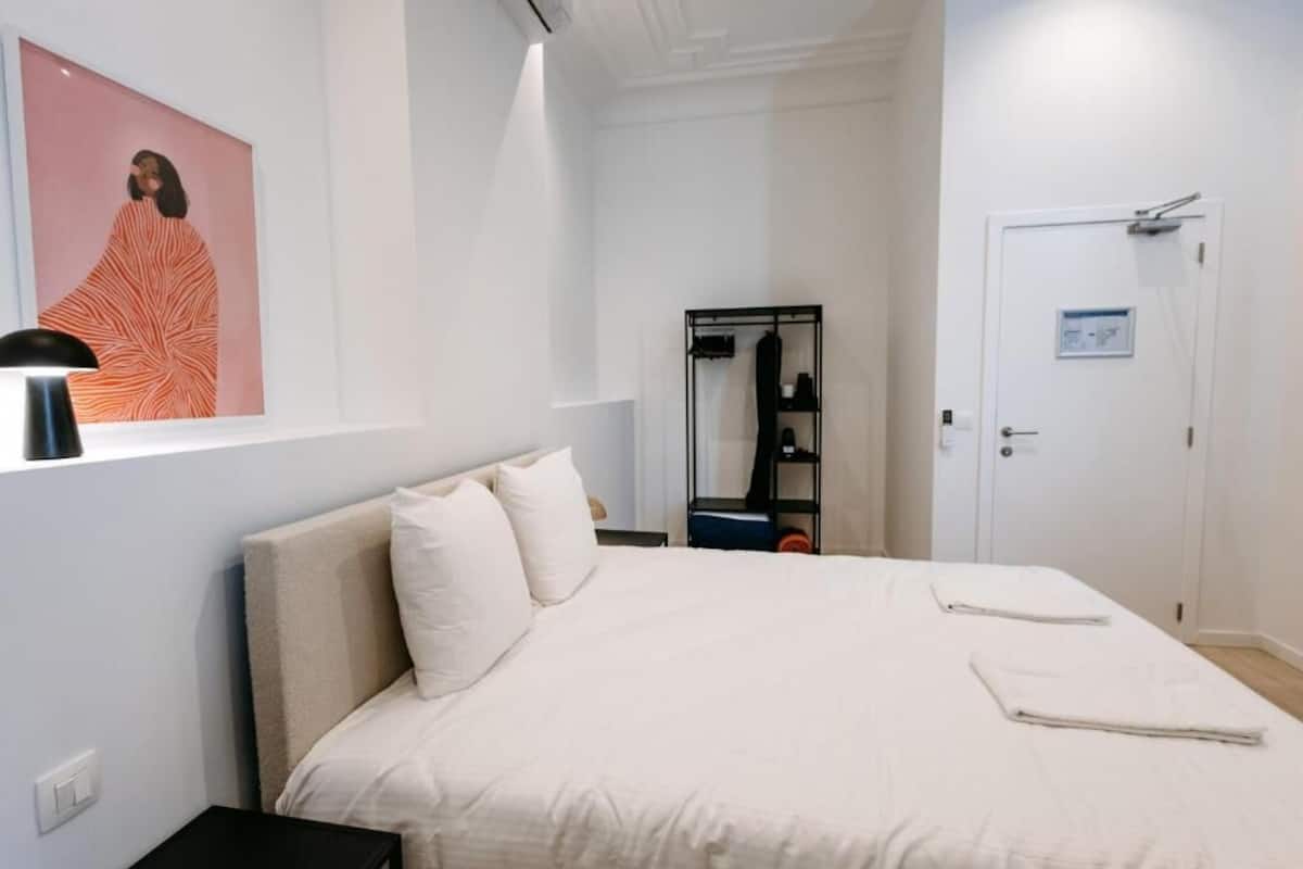 Une chambre d’hôtel avec un lit, une armoire, un miroir et une affiche accrochée au mur.