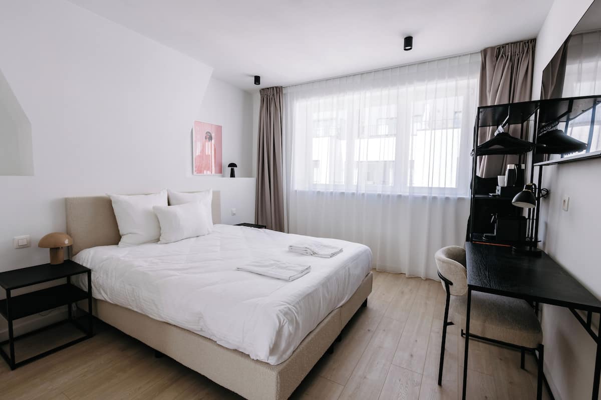 Une chambre d’hôtel moderne, dotée d’un grand lit, d’un bureau et d’une chaise.