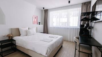 Una habitación de hotel moderna con una cama grande, un escritorio y una silla.