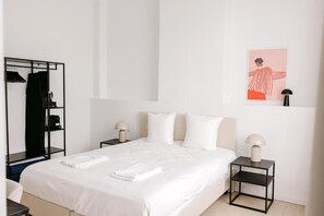 Une chambre d’hôtel comprenant un lit, deux tables de chevet, une armoire et une œuvre d’art accrochée au mur.