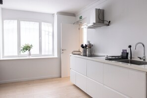 A modern kitchen with white cabinetry, a stainless steel sink, and a window with a view of the outside.