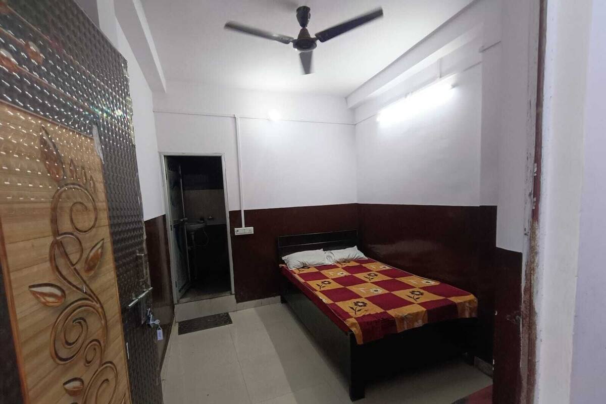 A bedroom with a bed, a ceiling fan, a door with decorative panels, and a small window.