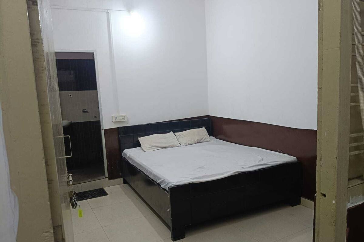 A bedroom with a bed, a mirror, and a door leading to a bathroom.