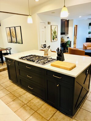 A modern kitchen with a large island, dark cabinetry, and a white countertop. - Cozy Fully Furnished 5B4B Palos Heights Oasis (Palos Heights)
