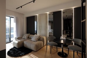 Ein modernes Wohnzimmer mit einer Couch, Sesseln, einem Esstisch und einem großen Spiegel.