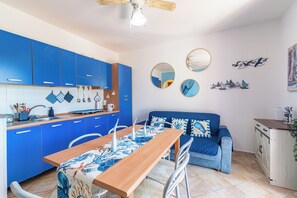Eine moderne Küche mit blauen Schränken, einem Holztisch und einem blauen Sofa.