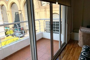 Ein Balkon mit Blick auf ein Gebäude mit Rundbogenfenstern, einem Kachelboden und einer Couch.