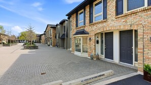 A residential street with brick houses, a paved walkway, and a 'NO VEHICLES BEYOND THIS POINT' sign. - Townhome with Parking Ideal for Longer Stays (Burlington)