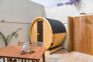 A wooden sauna with a black roof, a wooden table with plates and glasses, and a wooden fence. - The Tide House, Broadstairs (Broadstairs)