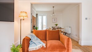Una sala de estar con sofá, lámpara, comedor y radiador.