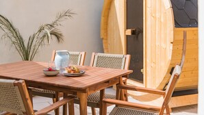 Una mesa de madera con sillas, un cuenco de fruta y una jarrón.