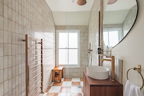 A bathroom with a tiled floor, a wooden stool, a large mirror, and a sink. - The Tide House, Broadstairs (Broadstairs)