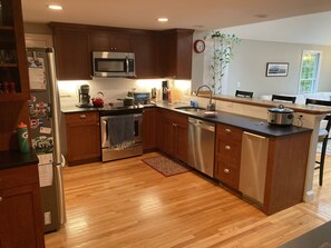 A modern kitchen with wooden cabinets, stainless steel appliances, and a wooden floor.