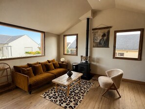 A living room with a sofa, a coffee table, a chair, a fireplace, and large windows. - Fisherman's house facing the sea (Saint-Côme-de-Fresné)