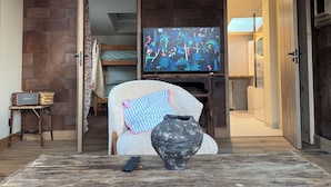 Ein Wohnzimmer mit Fernseher, einer Vase und einem Leopardenfellteppich.