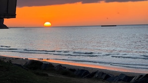 Ein Sonnenuntergang über dem Meer mit einem Strand im Vordergrund.