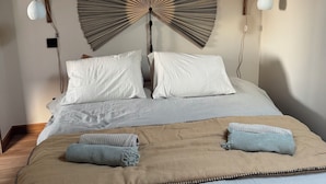 Ein Schlafzimmer mit einem großen Bett, zwei Nachttischlampen, einem Wandventilator und einer Deckenleuchte.