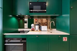 A kitchen with green cabinets, a microwave, a toaster, and a coffee maker. - Porto Urban Nest by Lisbeyond (Porto)