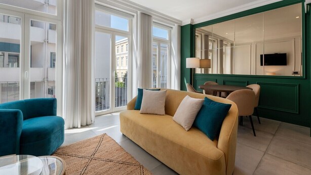 En moderne stue med sofa, stol, spisebord og fjernsyn.