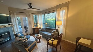 Una sala de estar con chimenea, sofá, sillones, una mesa de centro y televisor.