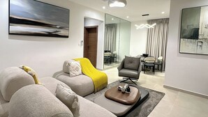 A modern living room with a sectional sofa, a coffee table, and a dining area in the background. - Dorville Hotel And Suites (Orerokpe)