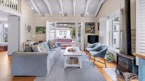 Ein geräumiges Wohnzimmer mit grauem Sofa, Couchtisch und Kamin. Ein Balkon bietet Blick ins Freie.