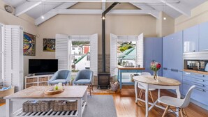 Ein modernes Wohnzimmer mit Fernseher, Sitzgelegenheiten und Kamin.